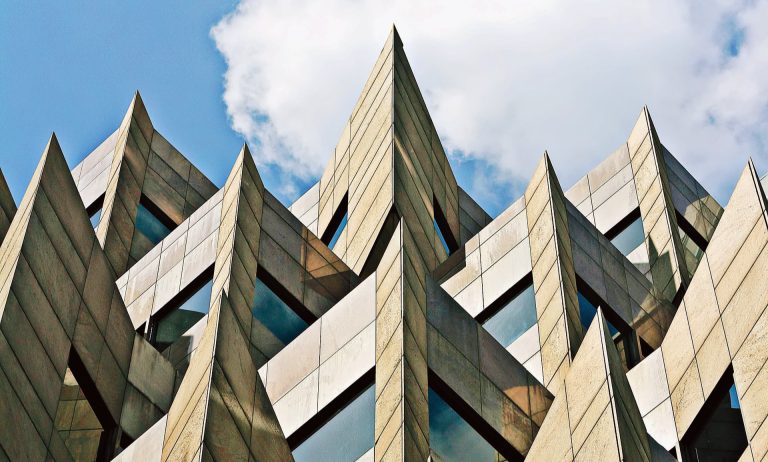 Architectural stone supply, template and fitting services page header, illustrated by a modern stone-clad glass building