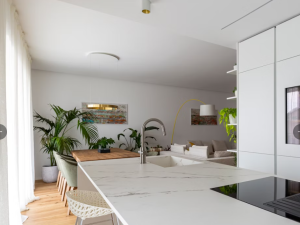 Dekton Kairos white marble-effect kitchen worktop in a modern, minimal kitchen setting with light grey walls and wood floors.