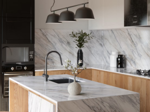Dekton Trance roomshot featuring a kitchen island and wall cladding in this material that is a white base with marble-veining