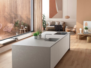 Silestone Poblenou roomshot featuring an open plan living space and a large kitchen island in the centre of the shot, next to a large floor-to-ceiling glass window to the yard outside.