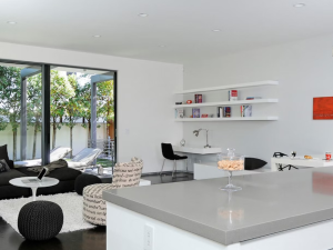 Open plan kitchen diner with white walls and cabinet doors, featuring a gris expo countertop on the room-facing kitchen island.