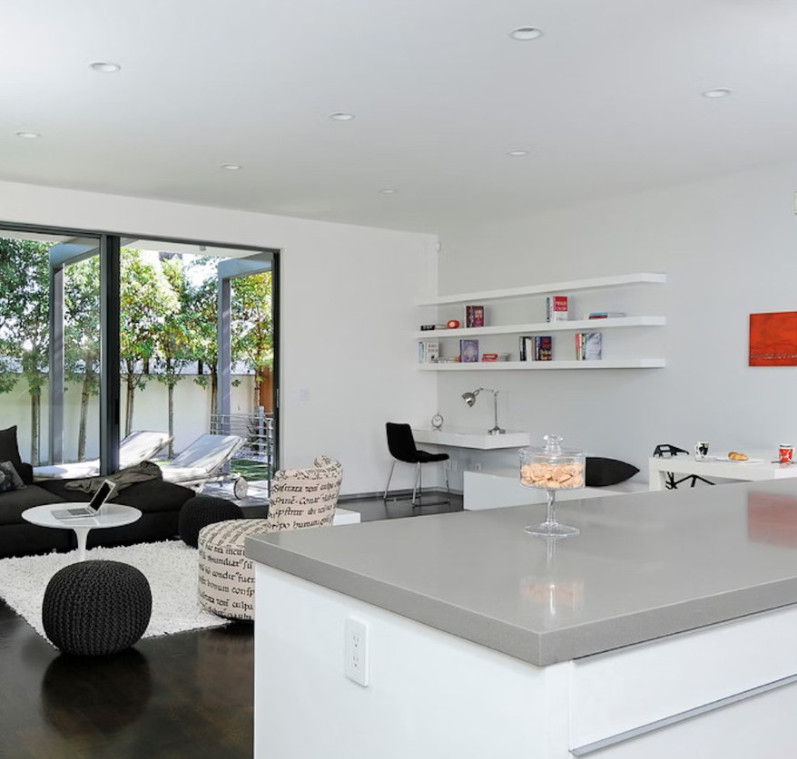 Open plan kitchen diner with white walls and cabinet doors, featuring a gris expo countertop on the room-facing kitchen island.