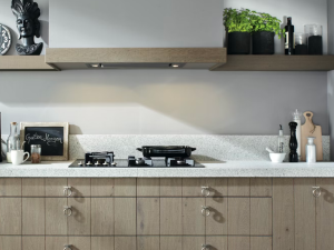 Silestone blanco norte worktops on a natural wood cabinet against a wall with matching wooden floating shelf on a light beige wall.