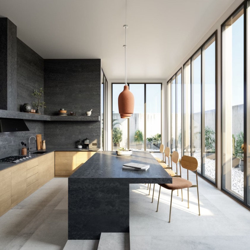 Silestone Earthis Raw D roomshot featuring a side-on kitchen breakfast bar in an open plan living space with floor-to-ceiling windows on the right and kitchen cabinets/shelves on the right, in charcoal and wood tones.