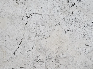 Fume Travertine - Grey (concrete grey) compact limestone ("travertine") with "cloud-shaped" structure due to typical pore structure. The surface contains small openings that may or may not be filled (pores are usually filled when placed with adapted grout). Fossils can be present throughout the material.